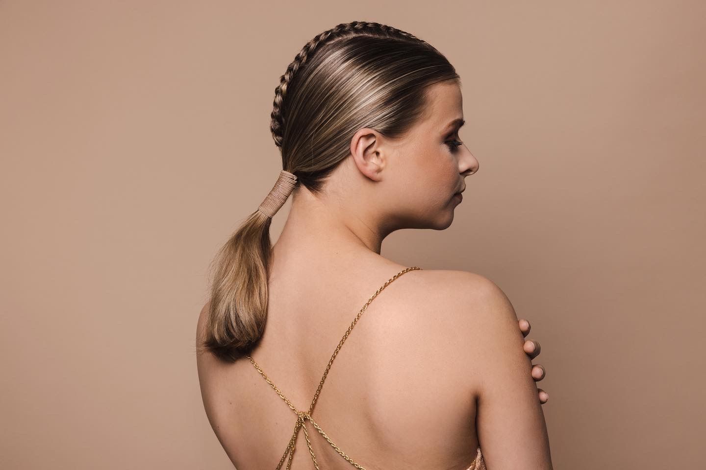 Model van achteren met een strak gevlochten, lage paardenstaart